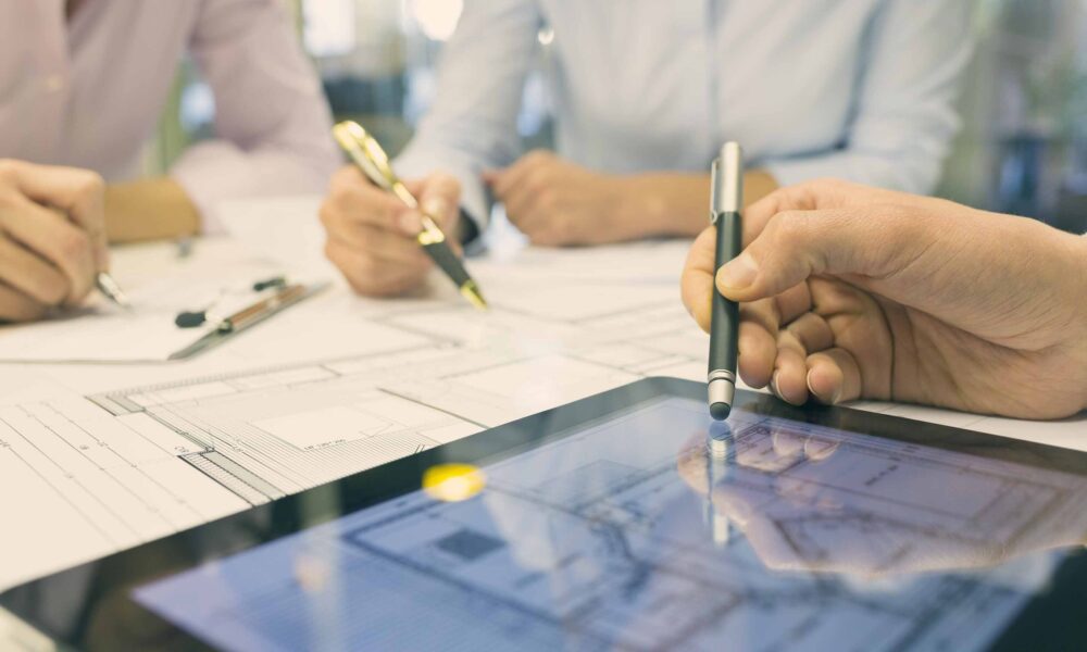 Close-up of Team architects working on construction project in o Business team desk architect man woman digital tablet blueprint construction